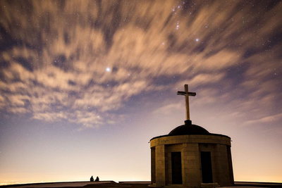 Eine Kirche mit Kreuz auf der Kuppel wird von einem sternenklaren Himmel beleuchtet.