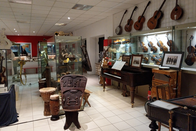 Raumansicht mit zahlreichen Musikinstrumenten, darunter Gitarren, Klaviere und Geigen