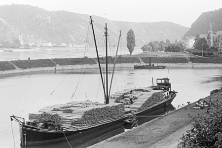 Schwarz-Weiß-Fotografie eines alten Frachtschiffs mit Baumstämmen in den 1930er Jahren im Stadthafen Sank Goar