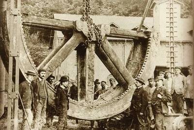 Meister und Arbeiter der Sayner Hütte in Krupp´scher Zeit (1865-1926) neben einem großen gusseisernen Stator, der für das Elektrizitätswerk in Peking auf der Sayner Hütte gegossen wurde; Fotografie von 1906